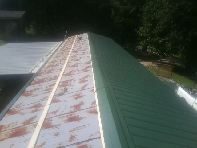 Old rusted panels beside newly installed green metal roofing — Wind Damage Roof Repair by Roofing Brothers in Evansville