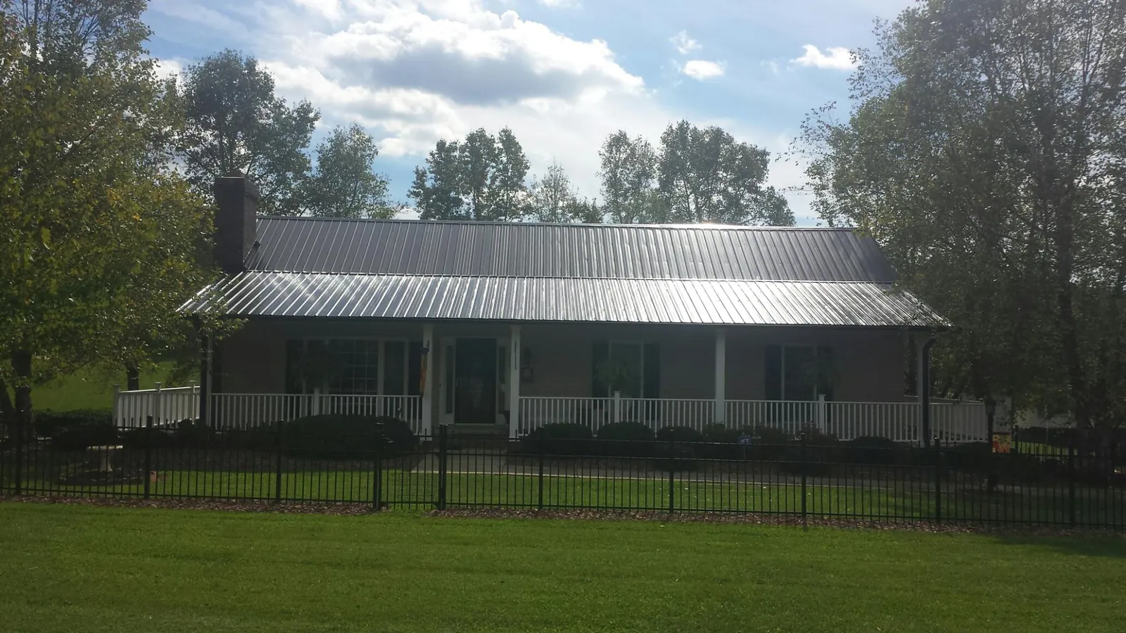 Gray metal roof on a brick ranch with a full width front porch — Gutter Guard Installation work by our crew in Evansville