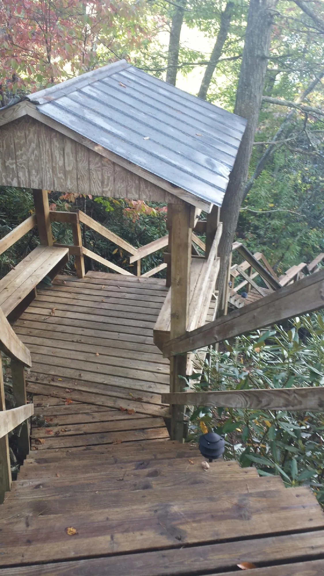 Metal roofed shelter over wooden steps on a wooded walkway — Skylight Repair & Installation work by our crew in Evansville